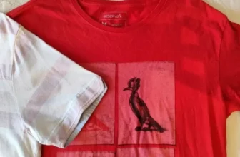 Close-up de uma camiseta vermelha da Reserva com a estampa do icônico pica-pau, símbolo da marca, disponível para compra com cupom de desconto.