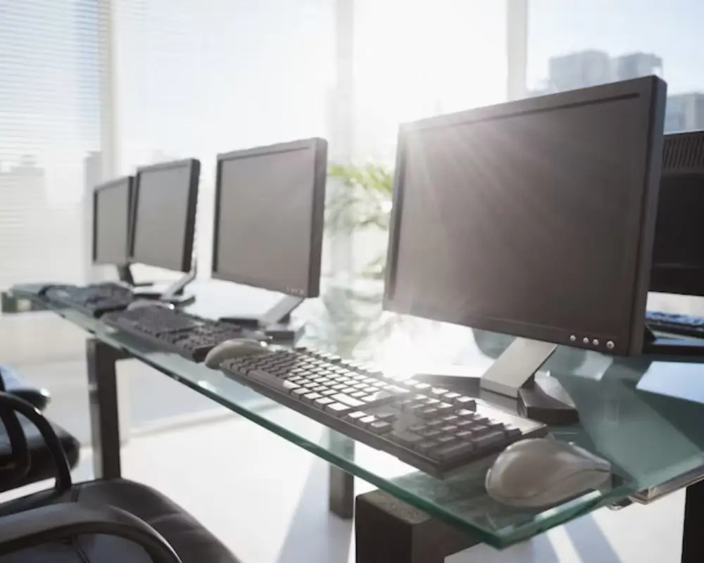 Computadores de escritório em uma mesa de vidro que podem ser comprados com cupom Gigantec