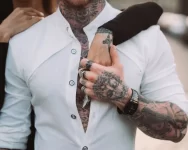 Homem estiloso com tatuagens usando camisa branca da Dafiti, representando as ofertas de moda masculina.