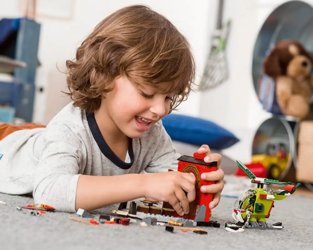 Criança feliz brincando após a compra com cupom de desconto Lego