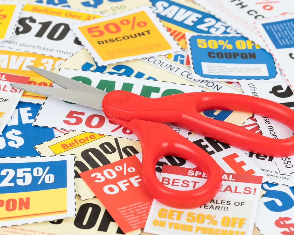 Uma mão segurando vários vouchers com o texto 'Cupom de Desconto', representando a variedade de cupons de primeira compra disponíveis.