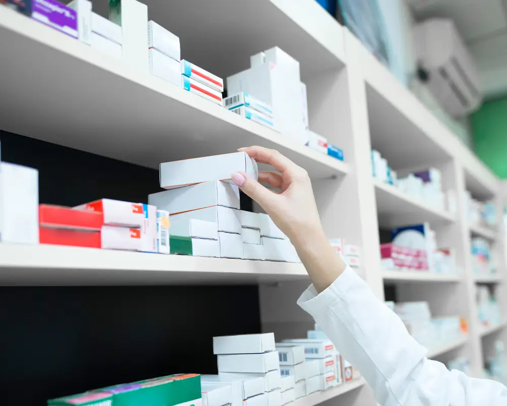 Farmacêutica organizando produtos em uma prateleira da Pague Menos, demonstrando a variedade de itens onde o cupom de desconto Pague Menos pode ser aplicado.