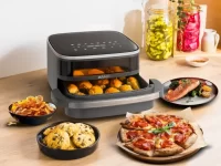 Fritadeira Elétrica Arno preta em uma bancada, mostrando sua versatilidade ao preparar diversos alimentos como pão de queijo, pizza e cookies. Um exemplo de produto para comprar usando um cupom de desconto Arno.