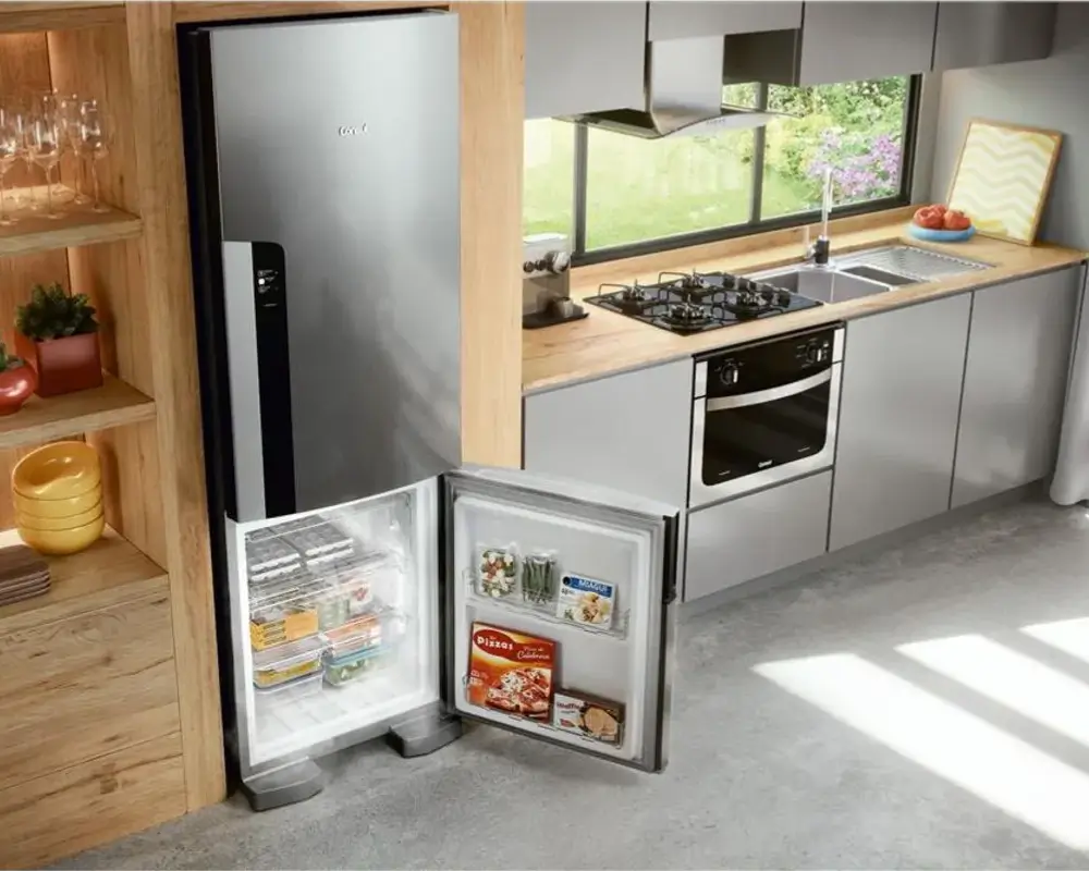 Geladeira Consul de inox em uma cozinha planejada, com a porta do freezer aberta, mostrando um exemplo de eletrodoméstico que pode ser comprado com cupom de desconto Consul.
