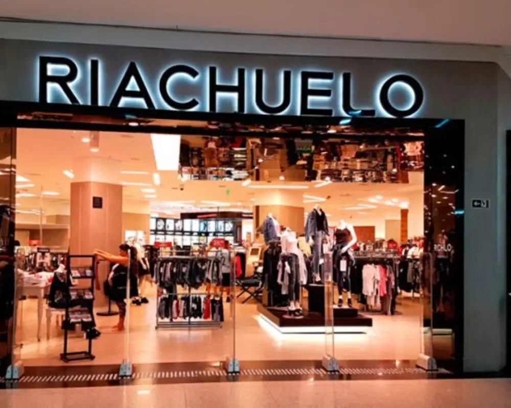 Fachada de uma loja Riachuelo em um shopping, mostrando a variedade de produtos de moda.