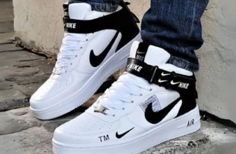 Tênis Nike Air Force 1 de cano alto nas cores branco e preto, nos pés de uma pessoa com calça jeans, destacando o modelo clássico da marca com desconto.