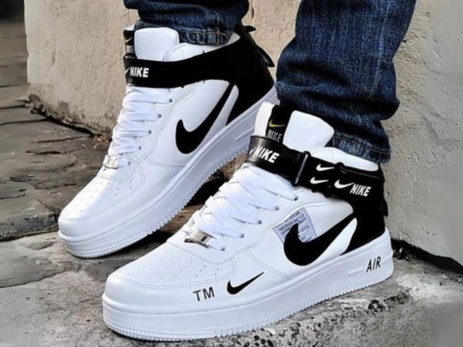 Tênis Nike Air Force 1 de cano alto nas cores branco e preto, nos pés de uma pessoa com calça jeans, destacando o modelo clássico da marca com desconto.